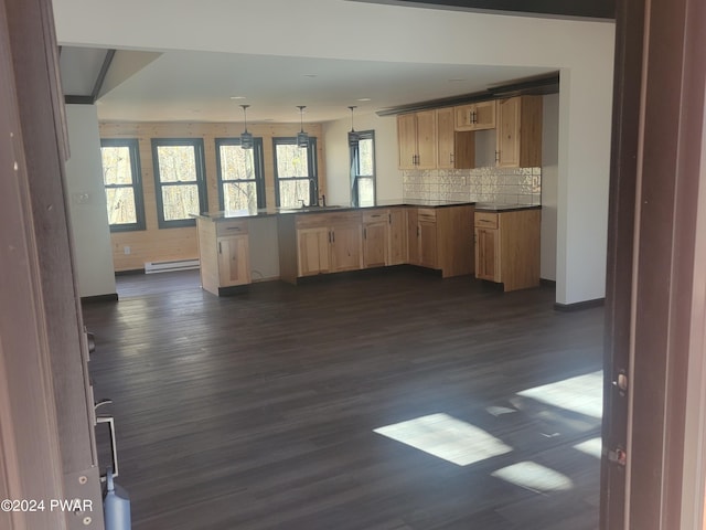 kitchen featuring dark hardwood / wood-style flooring, kitchen peninsula, decorative light fixtures, decorative backsplash, and light brown cabinetry