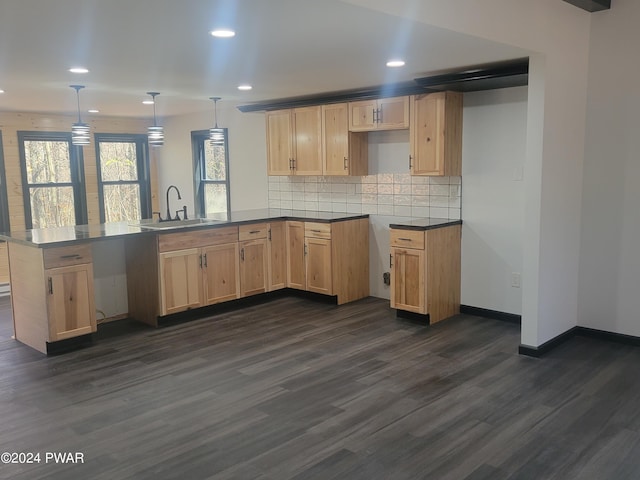 kitchen with kitchen peninsula, dark hardwood / wood-style floors, hanging light fixtures, and sink