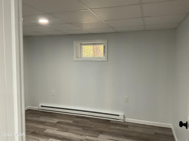 empty room featuring a drop ceiling, hardwood / wood-style flooring, and baseboard heating