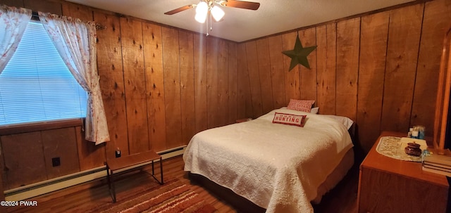 bedroom featuring dark wood-type flooring, wooden walls, ceiling fan, and baseboard heating