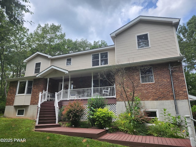 216 Comstock Dr, Lords Valley, PA 18428 - view of front of home with brick siding, stairway, covered porch, and a front lawn