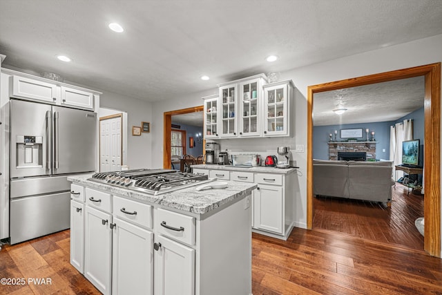 216 Comstock Dr, Lords Valley, PA 18428 - kitchen with appliances with stainless steel finishes, hardwood / wood-style floors, glass insert cabinets, a stone fireplace, and recessed lighting