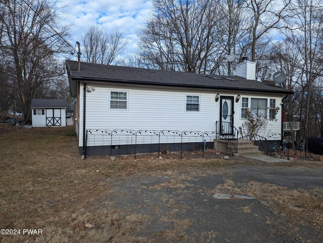 view of front of property featuring a storage shed