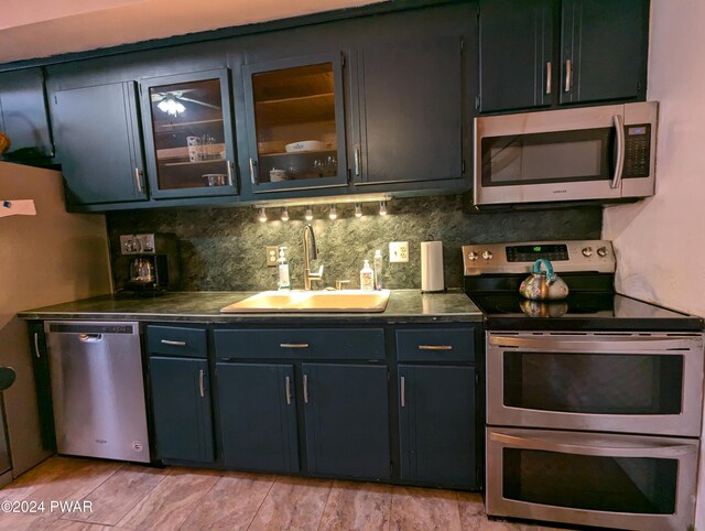 kitchen featuring backsplash, sink, stainless steel appliances, and light wood-type flooring