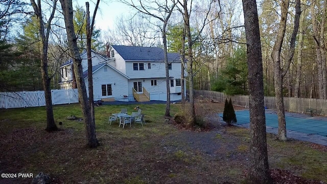 back of property featuring a lawn and a covered pool