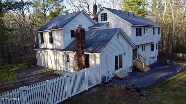 rear view of property with ac unit and a garage