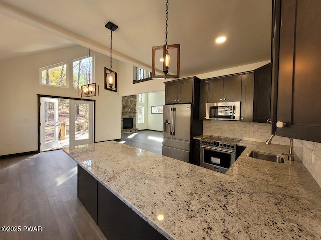 kitchen featuring sink, light stone counters, pendant lighting, decorative backsplash, and high end appliances