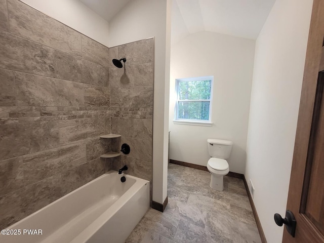 bathroom with toilet, vaulted ceiling, and tiled shower / bath