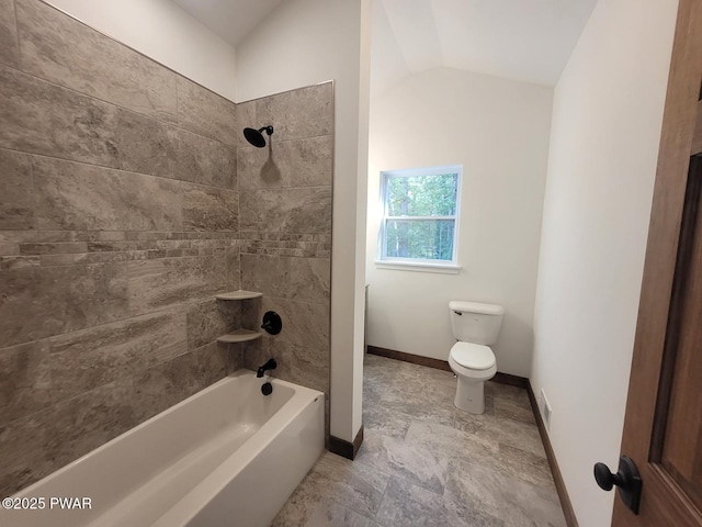 bathroom featuring toilet, lofted ceiling, and tiled shower / bath