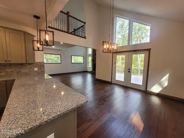 interior space with light stone counters, hanging light fixtures, a high ceiling, and french doors