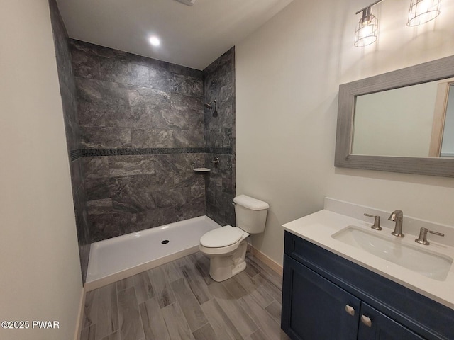 bathroom featuring vanity, toilet, and tiled shower