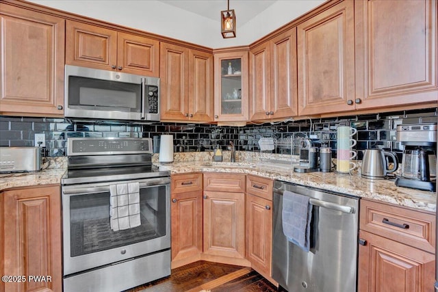 kitchen featuring decorative backsplash, dark hardwood / wood-style floors, light stone counters, and appliances with stainless steel finishes