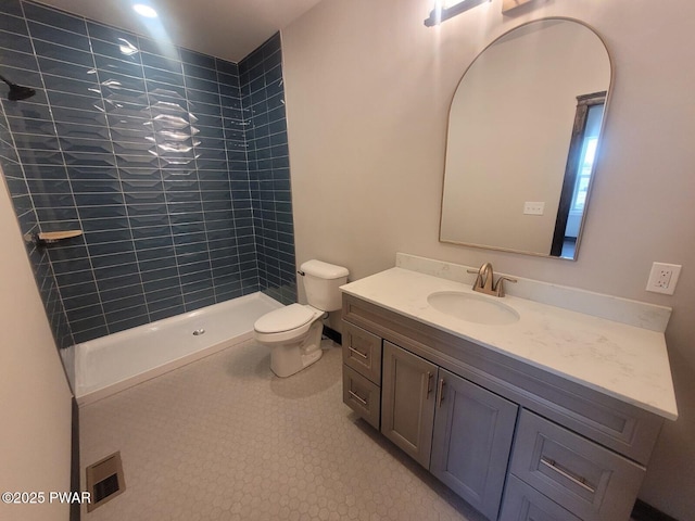 bathroom with a tile shower, tile patterned floors, vanity, and toilet