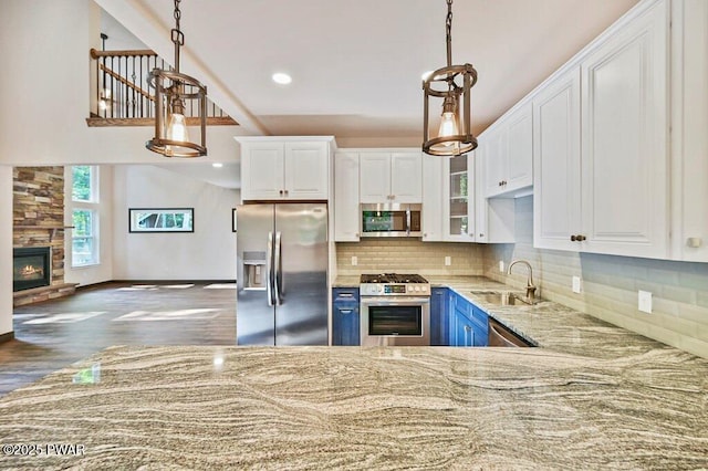 kitchen with blue cabinetry, white cabinetry, sink, stainless steel appliances, and pendant lighting