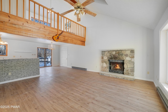 unfurnished living room featuring a fireplace, hardwood / wood-style flooring, ceiling fan with notable chandelier, and baseboard heating