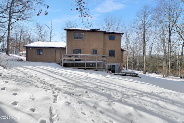 snow covered rear of property with a wooden deck