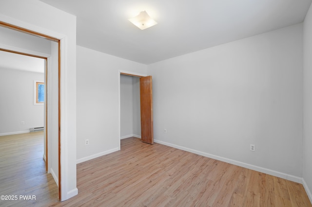 unfurnished room with a baseboard radiator and light hardwood / wood-style flooring