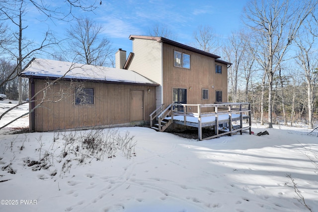 snow covered rear of property with a wooden deck