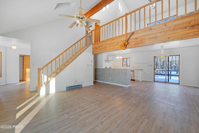 unfurnished living room with hardwood / wood-style flooring, a towering ceiling, a baseboard radiator, and ceiling fan with notable chandelier