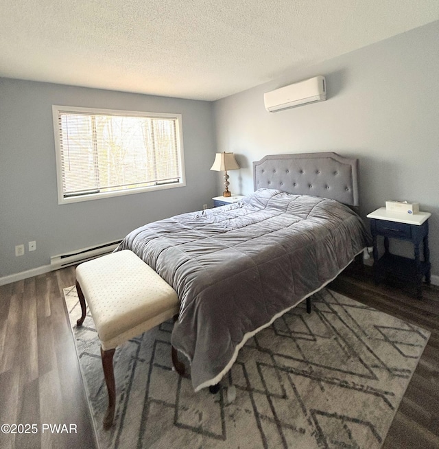 bedroom with a baseboard heating unit, baseboards, a wall mounted air conditioner, wood finished floors, and a textured ceiling