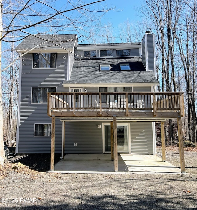 view of front of home featuring a deck, a patio, a carport, and a chimney