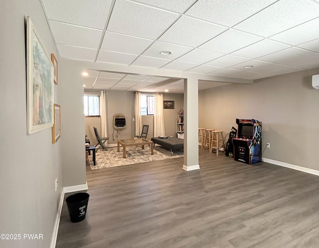 exercise room with a paneled ceiling, baseboards, and wood finished floors