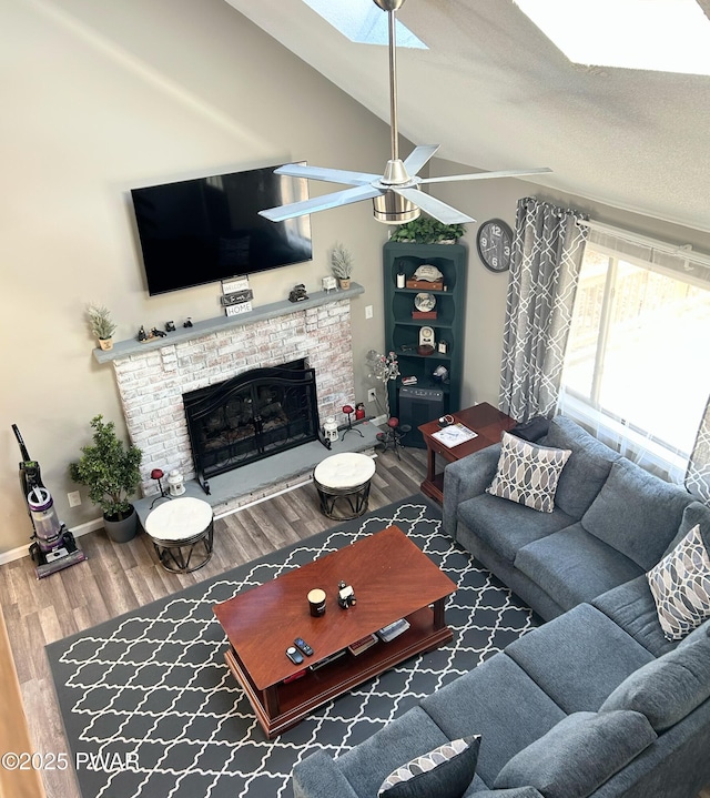 living area with wood finished floors, a fireplace, baseboards, ceiling fan, and vaulted ceiling