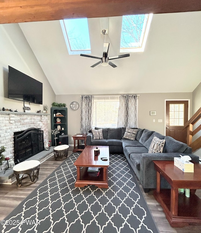 living room with a brick fireplace, a skylight, wood finished floors, and high vaulted ceiling