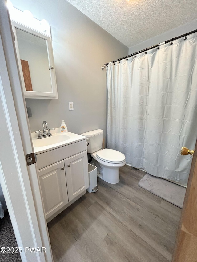 bathroom featuring vanity, a shower with shower curtain, wood finished floors, a textured ceiling, and toilet