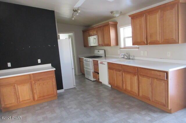 kitchen with vaulted ceiling, white appliances, track lighting, and sink