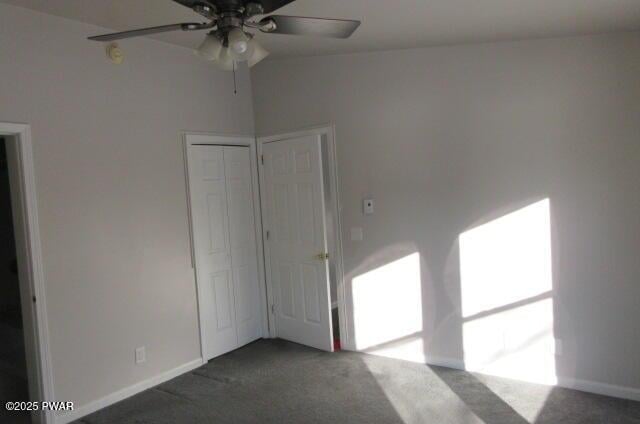 empty room with ceiling fan and dark carpet