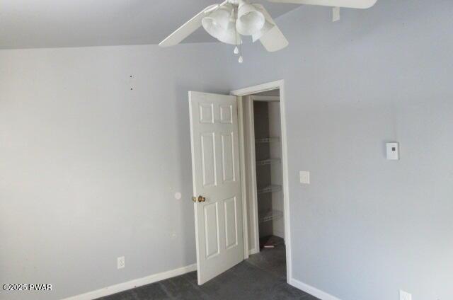 spare room with ceiling fan and dark colored carpet