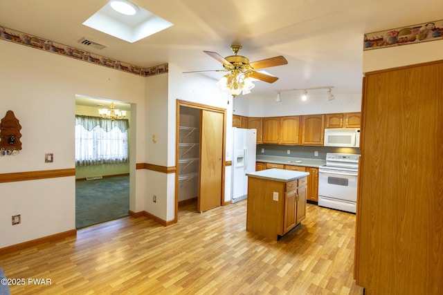 kitchen with white appliances, a kitchen island, visible vents, light wood-style floors, and light countertops