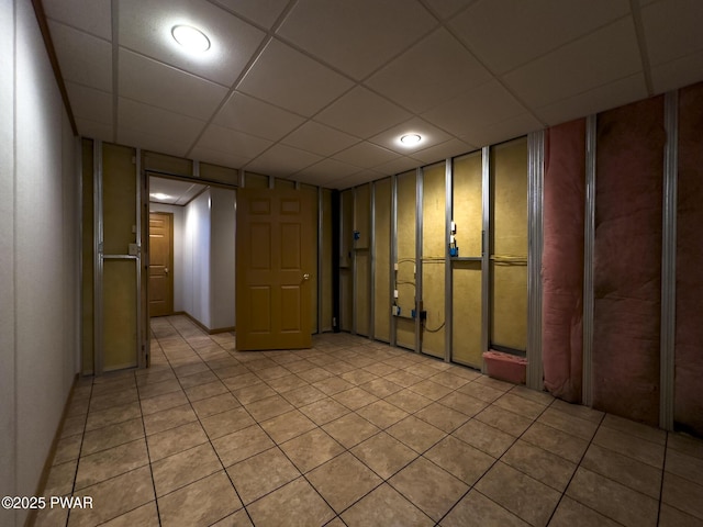 finished basement featuring a paneled ceiling and light tile patterned floors