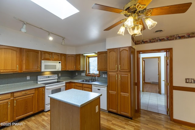 kitchen with light wood-type flooring, white appliances, brown cabinets, and a sink