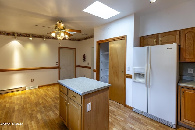 kitchen with white refrigerator with ice dispenser, visible vents, brown cabinetry, a baseboard radiator, and light wood-style floors