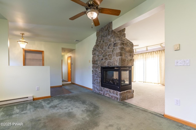 unfurnished living room featuring baseboard heating, carpet flooring, a stone fireplace, and baseboards