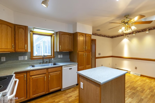 kitchen featuring white appliances, visible vents, brown cabinetry, light wood-type flooring, and a sink