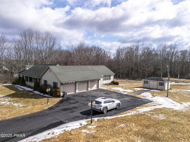 ranch-style house with aphalt driveway and an outbuilding