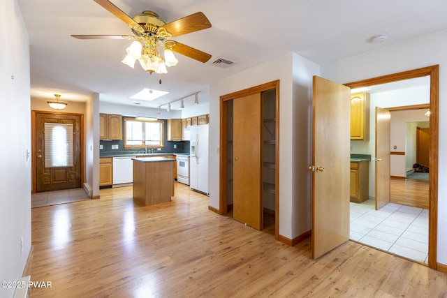 kitchen with white appliances, a kitchen island, visible vents, light wood-type flooring, and tasteful backsplash