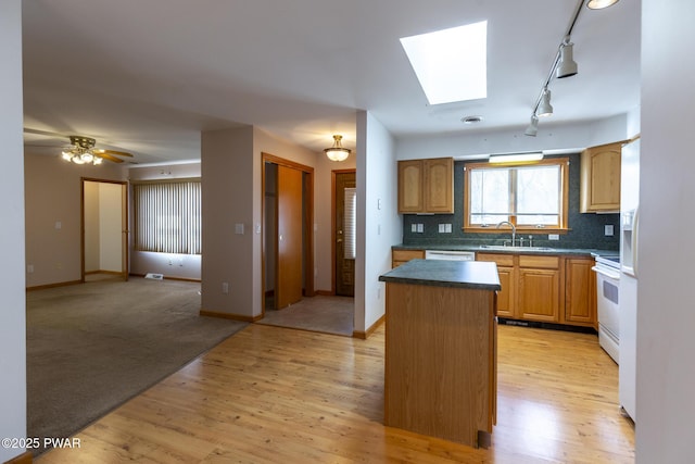 kitchen featuring light wood-style flooring, white appliances, a sink, a center island, and tasteful backsplash