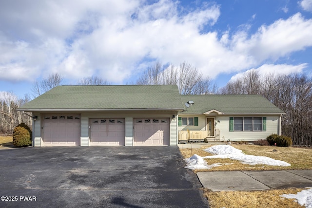 ranch-style house with driveway, an attached garage, and roof with shingles