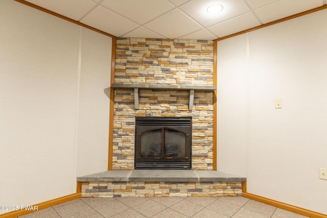 room details featuring a drop ceiling, a stone fireplace, and baseboards