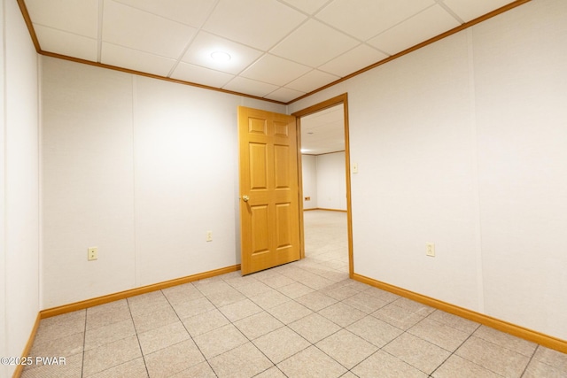 unfurnished room with a paneled ceiling, crown molding, and baseboards