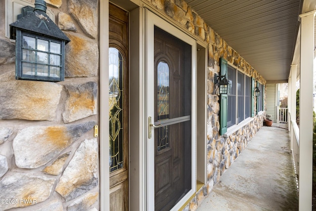 property entrance featuring stone siding and a porch