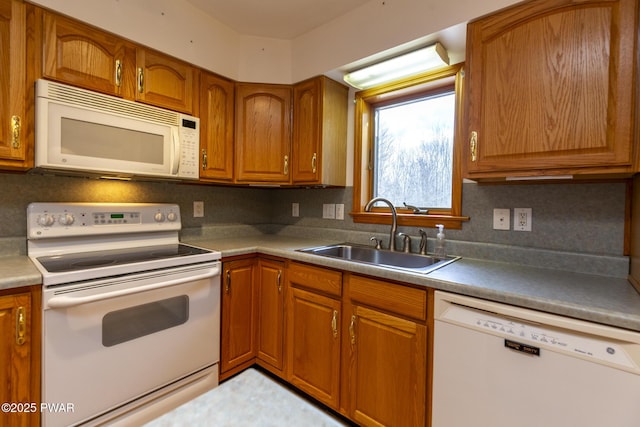 kitchen featuring white appliances, decorative backsplash, a sink, and brown cabinets