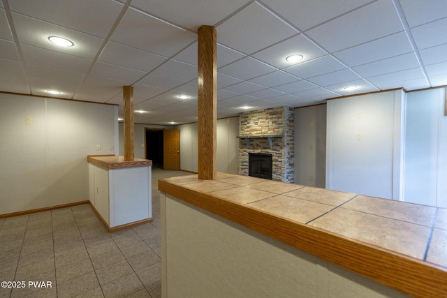 kitchen featuring a fireplace, tile counters, a paneled ceiling, recessed lighting, and white cabinetry