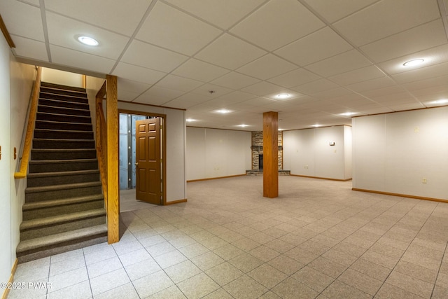 finished basement featuring baseboards, stairway, a drop ceiling, and recessed lighting