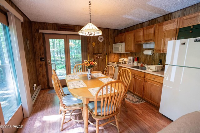 28 Lakewood Dr, Lake Ariel, PA 18436 - dining space featuring wood walls, a textured ceiling, a baseboard radiator, and light wood-type flooring