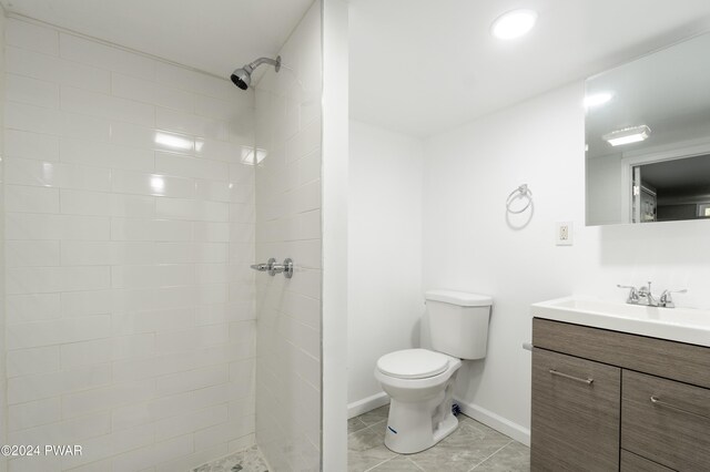 bathroom featuring tiled shower, tile patterned floors, vanity, and toilet